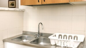 Una cocina con dos lavamanos de acero inoxidable, armarios de madera y encimera blanca.