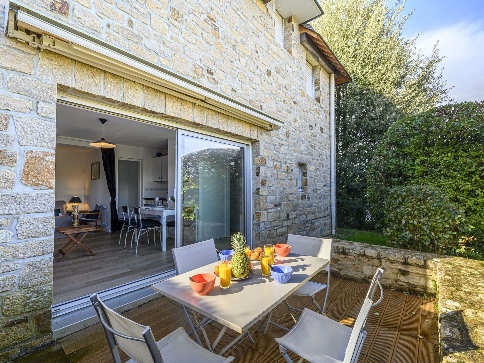 Een stenen huis met een patio, voorzien van een tafel met stoelen, een eettafel en een glazen deur die naar de binnenruimte leidt.