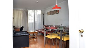 A modern living room with a dining area, featuring a red pendant light, leather sofa, and yellow chairs. - The Golf with large terrace (Las Condes)