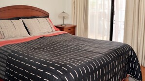 A bedroom with a large bed, a nightstand, a lamp, a window with curtains, and a ceiling light. - The Golf with large terrace (Las Condes)