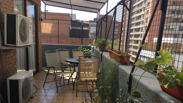 A patio area with a table and chairs, potted plants, and air conditioning units. - The Golf with large terrace (Las Condes)