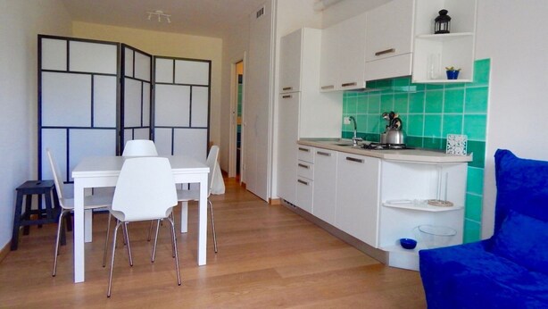 A compact kitchen with white cabinets, a green backsplash, and a dining area with a white table and chairs. - S127 - Sirolo, brand new studio with terrace (Sirolo)