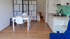A compact kitchen with a dining area, white cabinetry, and a blue chair. - S127 - Sirolo, brand new studio with terrace (Sirolo)