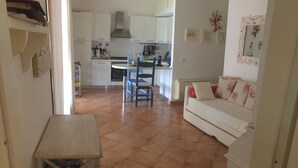 Un espai vital compacte amb zona de cuina, taula de menjador i sofà.