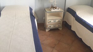 Habitació amb dos llits, una tauleta de nit amb una làmpada i un quadre penjat a la paret.