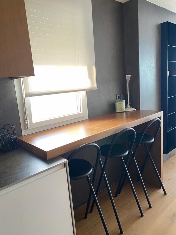 A kitchen with a wooden countertop, a window with blinds, a white refrigerator, and two black bar stools. - LUXURY APARTMENT APARTMENT 11 with direct views of the sea, sunrises live. (GANDIA PLAYA)