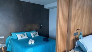 A modern hotel room with a large bed, a small round table, and a wooden panel wall. - LUXURY APARTMENT APARTMENT 11 with direct views of the sea, sunrises live. (GANDIA PLAYA)