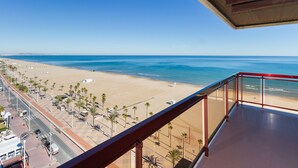 A beach view from a balcony with a red railing, palm trees, and a clear blue sky. - LUXURY APARTMENT APARTMENT 11 with direct views of the sea, sunrises live. (GANDIA PLAYA)