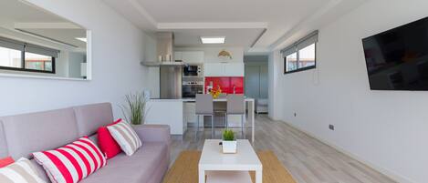 Een modern appartement met een woonkamer, kitchenette en een eethoek.