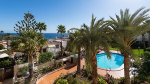A swimming pool surrounded by palm trees, with a view of the sea in the background. - Aguila Beach Ocean View By CanariasGetaway (Maspalomas)