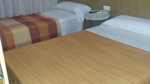 A hotel room with two single beds, a wooden table, a nightstand, and a curtain. - Holiday home Villa Carmeli (Ardales)