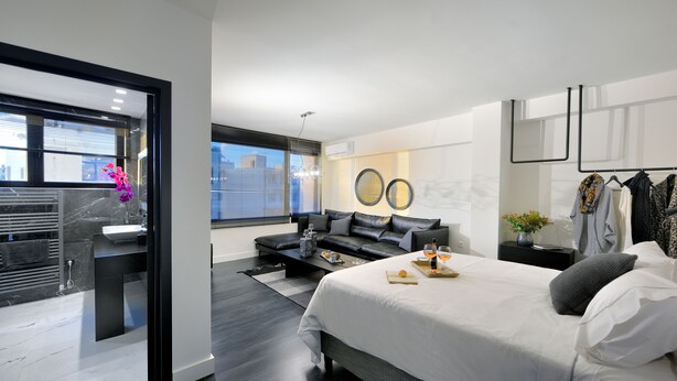 Un dormitorio moderno con una cama grande, un área de descanso y un baño con tocador.
