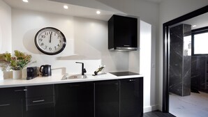 Una cocina moderna con armarios negros, una encimera blanca, un reloj negro y una campana extractora negra.