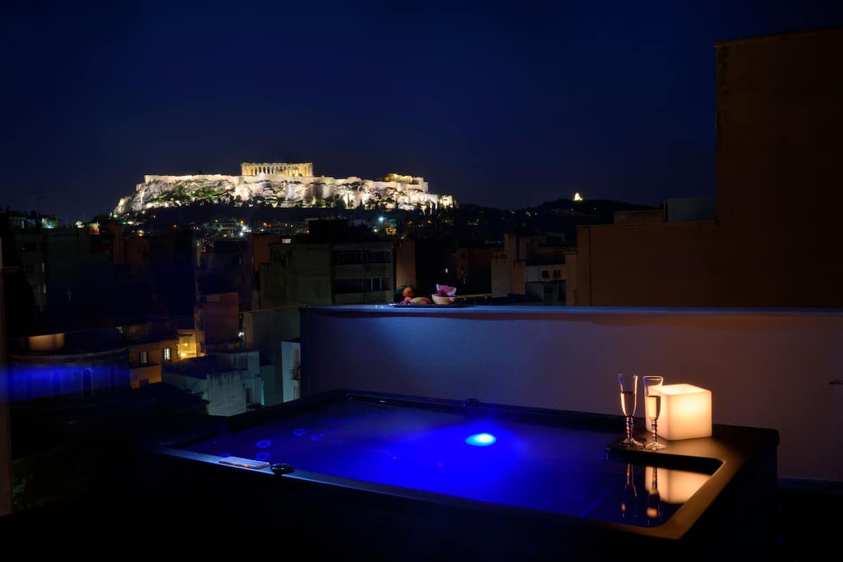 A rooftop bar with a view of a historic building at night.