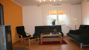 Ein Wohnzimmer mit Kamin, zwei schwarzen Sofas, einem Holztisch und einem roten Teppich.