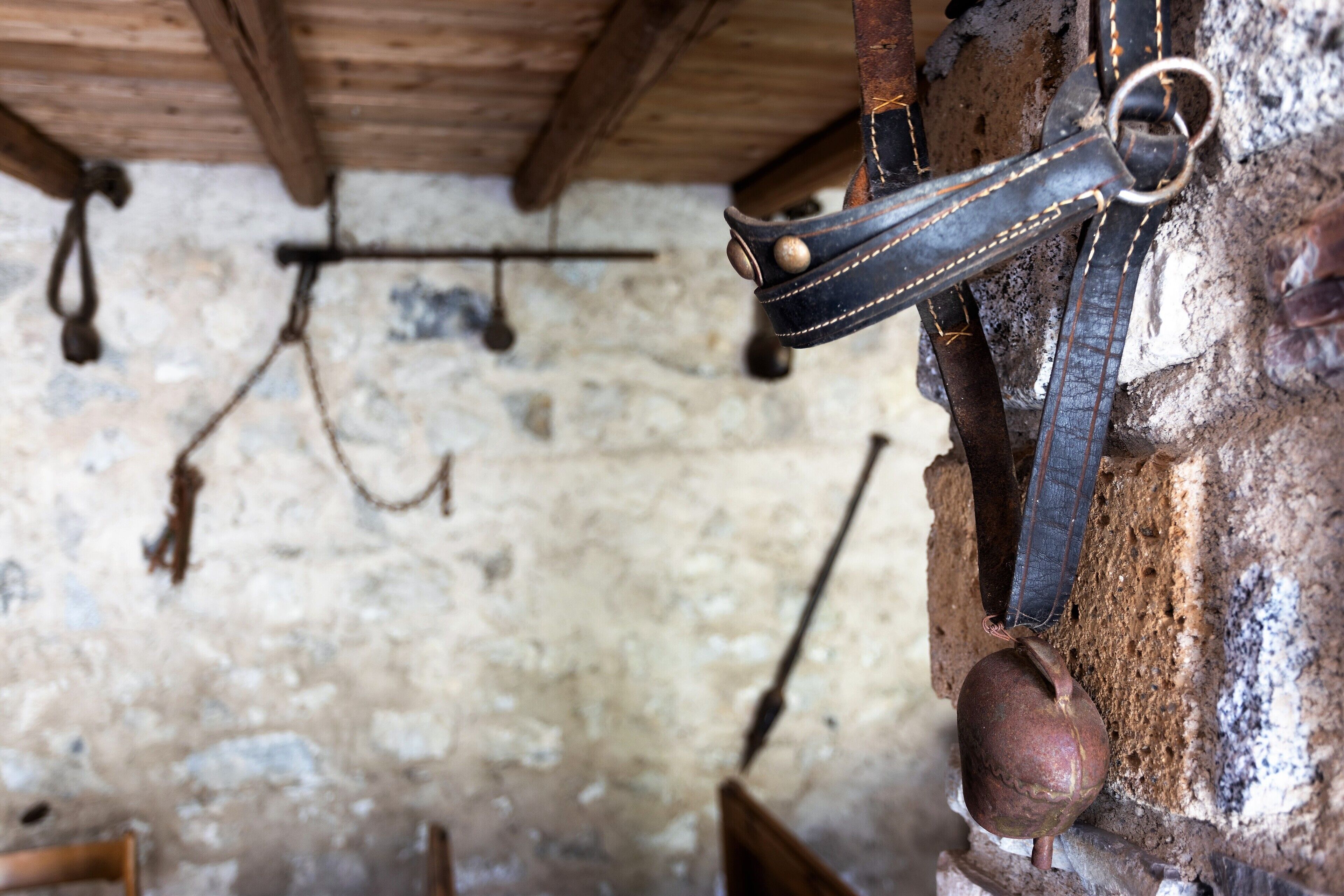 A rustic interior with exposed brick walls, wooden beams, and leather straps hanging on the wall.