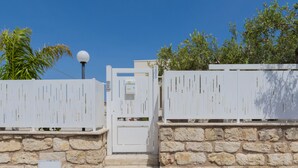 A stone wall with a white gate, a small white sign, and a spherical light fixture. - Brand new villa with private pool and terrace Alcamo marina (Alcamo)
