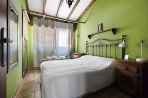 A room with a bed, a bedside table, a lamp, a window with curtains, and a door. - Quiet house by the sea / beach, WiFi, child-friendly, terrace - great location (Alcalá)