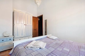 Une chambre à coucher comprenant un lit, une armoire, un miroir et une porte donnant sur une autre pièce.
