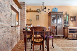 Un coin repas avec un mur en briques, une table en bois, des chaises et un lustre.