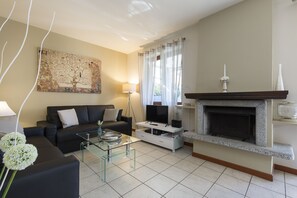 Una sala de estar con sofá, televisor, chimenea y obras de arte.