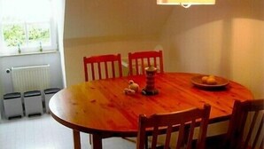 Een ronde houten eettafel met vier stoelen, een klein decoratief object en een bord met citroenen.