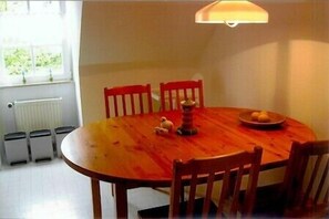 A round wooden dining table with four chairs, a small decorative item, and a plate with lemons on it.
