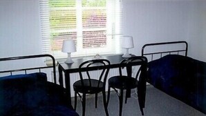 Een kamer met twee eenpersoonsbedden, een tafeltje met een lamp en een stoel.