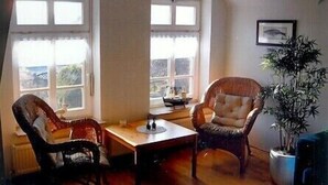 Een kamer met twee rieten stoelen, een tafeltje en een potplant.