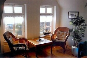 A room with two wicker chairs, a small table, and a potted plant.
