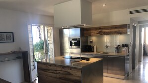 Une cuisine moderne dotée d’un îlot central, d’appareils électroménagers en acier inoxydable et d’un mur d’accent en bois.