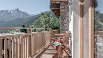 A balcony with wooden railings, a table, and two chairs.