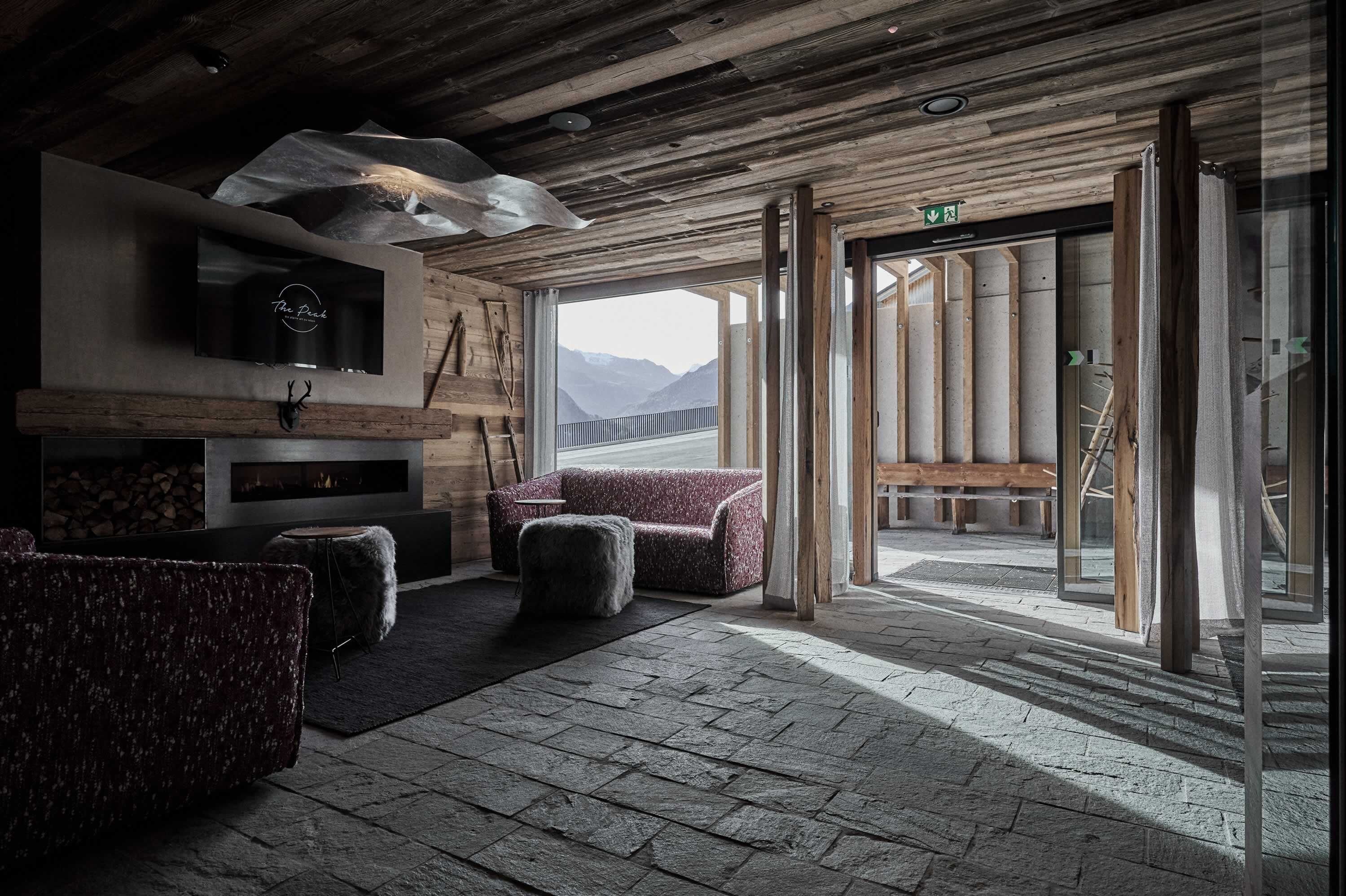 A rustic interior with a fireplace, seating area, and a view of mountains.