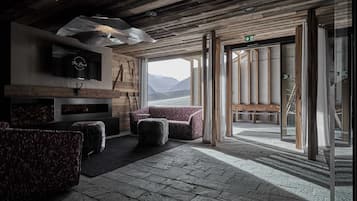A rustic interior with a fireplace, seating area, and a view of mountains.
