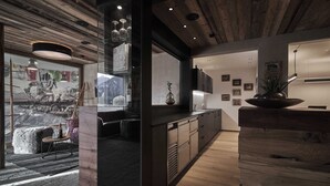 Une cuisine moderne avec des meubles en bois, un four encastré et une grande fenêtre donnant sur un paysage enneigé.