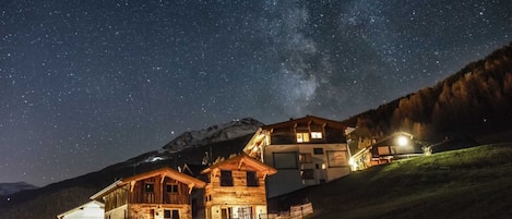 A mountain lodge with multiple buildings, a visible mountain, and a starry night sky.