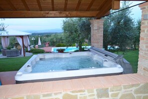 Relax in a hot tub surrounded by lush greenery and a serene swimming pool.