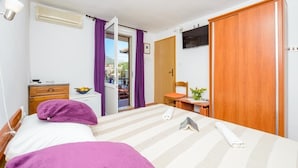 A bedroom with a bed, a desk, a chair, a wardrobe, and a television. - Room in Cavtat with Seaview, Balcony, Air condition, WIFI (3686-1) (Cavtat)
