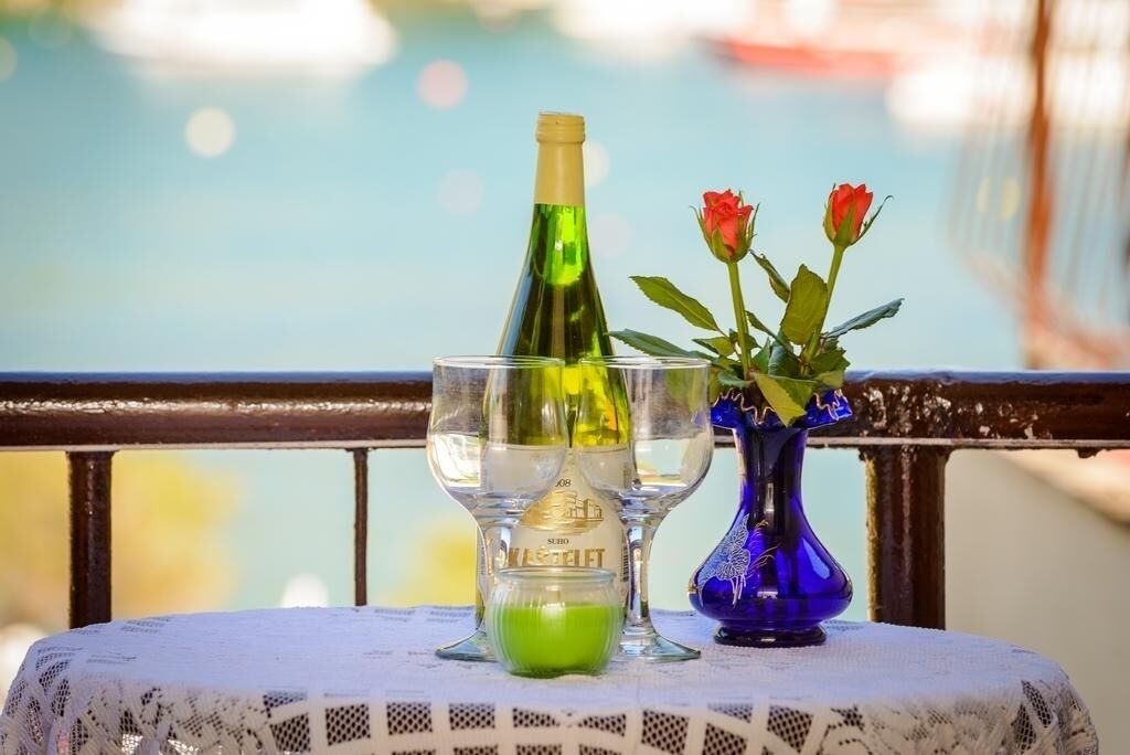 Une table avec une bouteille, un verre et un vase rempli de fleurs.