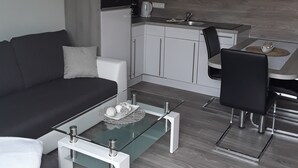 Ein modernes Wohnzimmer mit einem Glastisch, einer Couch und einem Essbereich mit einem Stuhl und Tisch.
