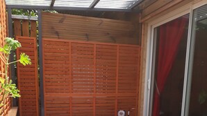 A hot tub with a wooden deck, surrounded by a wooden fence, and a potted plant in the foreground. - la cariole (Saint-Pierre)