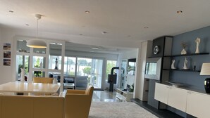 A modern kitchen with a central island, yellow chairs, and a large window. - Luxurious holiday home directly on the lake (Wervershoof)