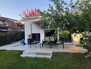 A modern house with a patio, outdoor seating, and a garden.