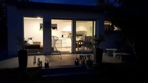 Ein modernes Haus mit Glastür, die zu einer Küche und einem Wohnbereich führt.