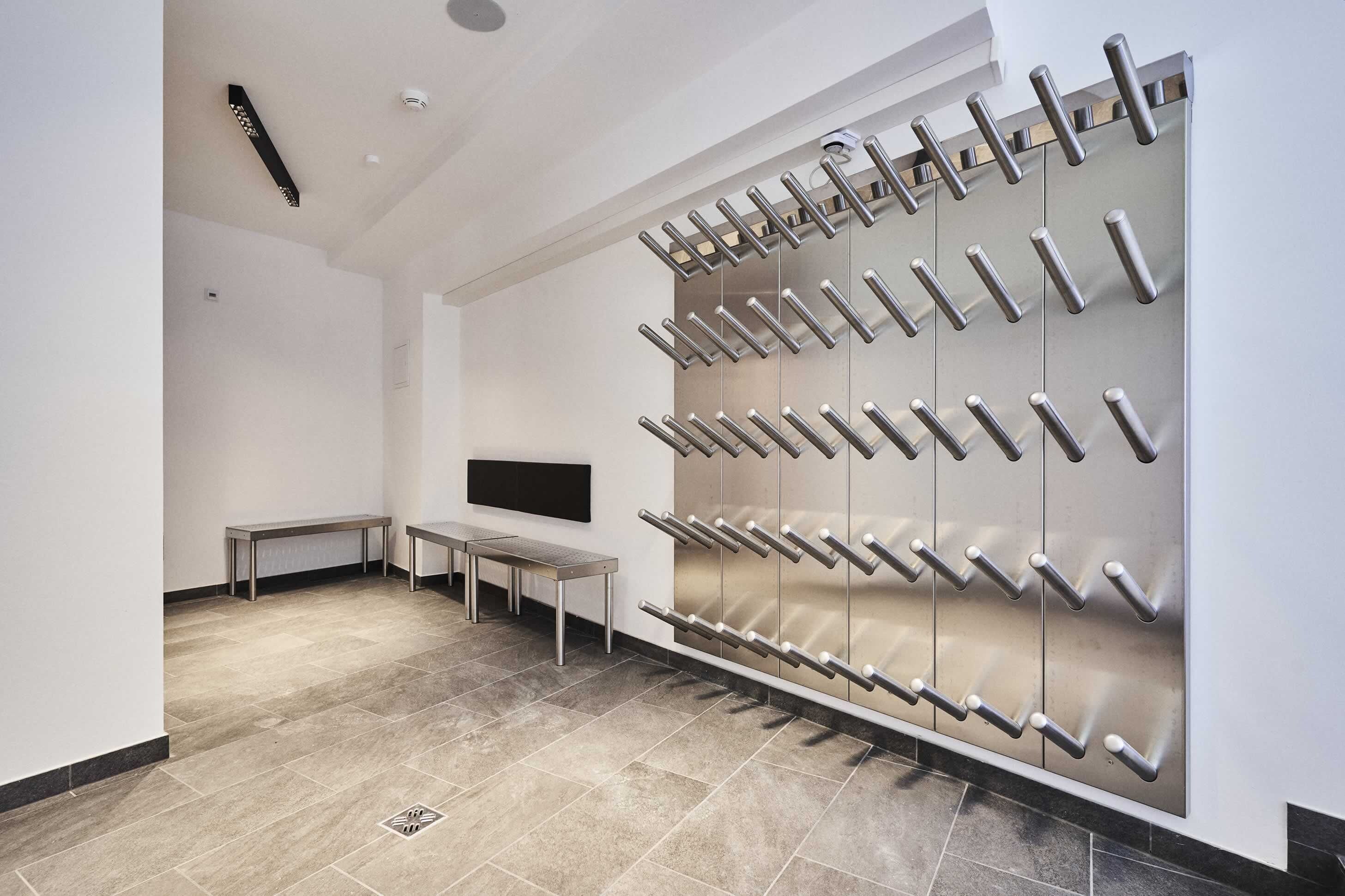A modern bathroom with a large mirror, a bench, and a wall-mounted towel rack.