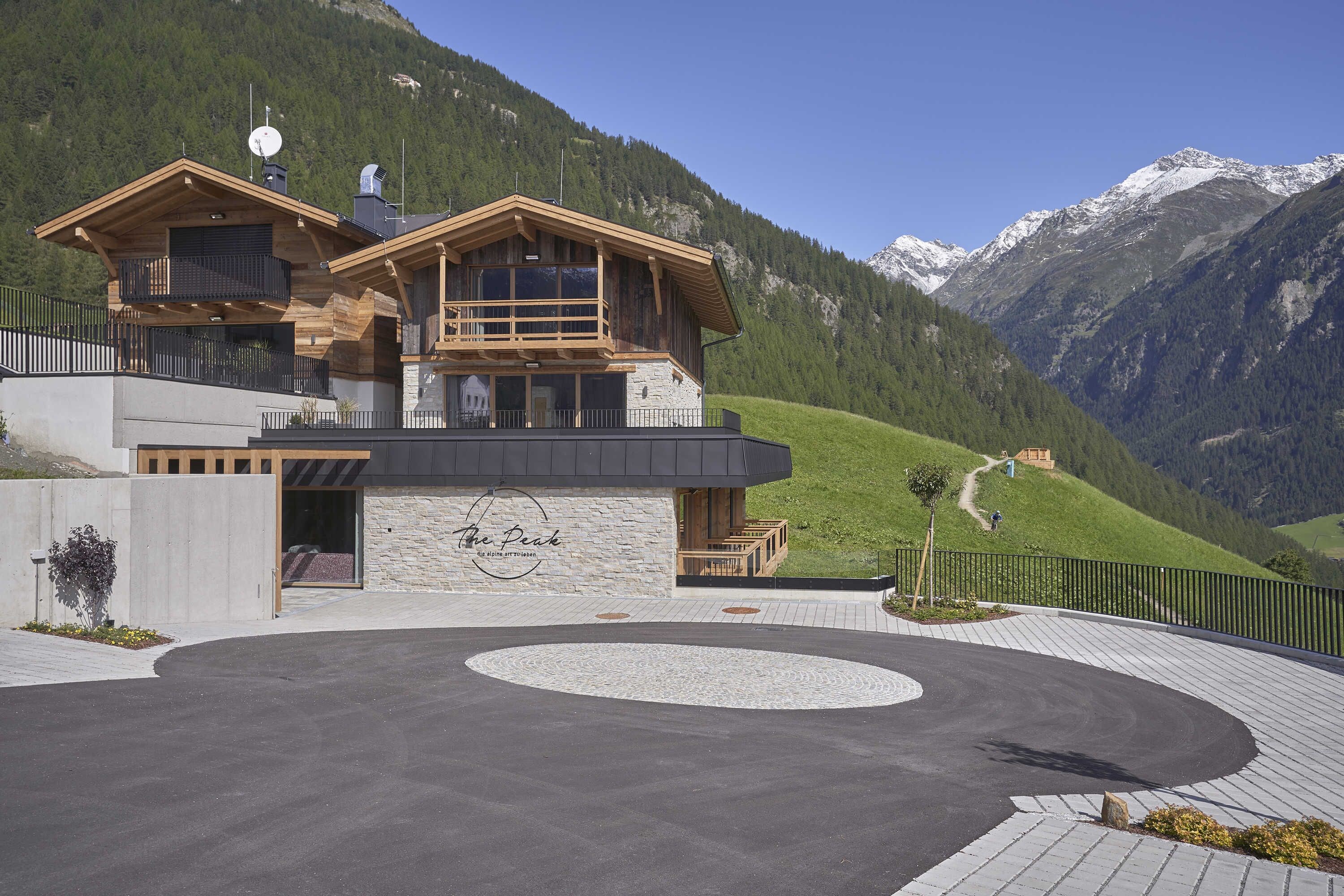 A modern lodge with a stone facade, wooden balconies, and a view of a mountainous landscape.