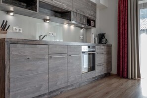 Una cocina moderna con electrodomésticos integrados, armarios de madera y un ventanal con cortinas.