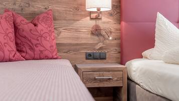Une chambre à coucher avec une tête de lit en bois, une lampe de chevet, une table de chevet avec un tiroir et un lit avec une literie rose et blanche.