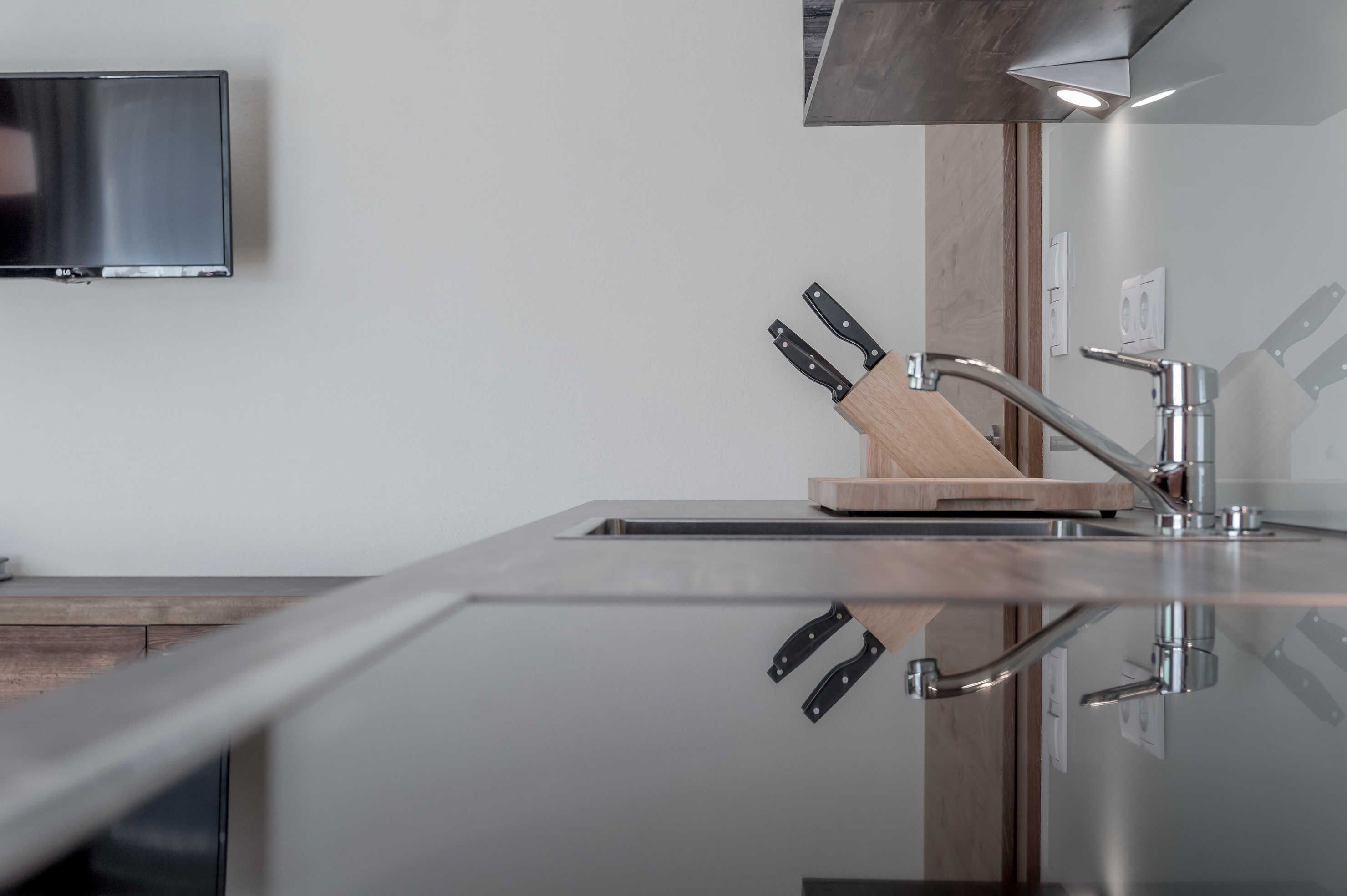 A modern kitchen with a stainless steel sink, wooden cutting board, and a knife block.