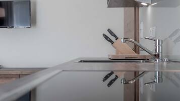 A modern kitchen with a stainless steel sink, wooden cutting board, and a knife block.